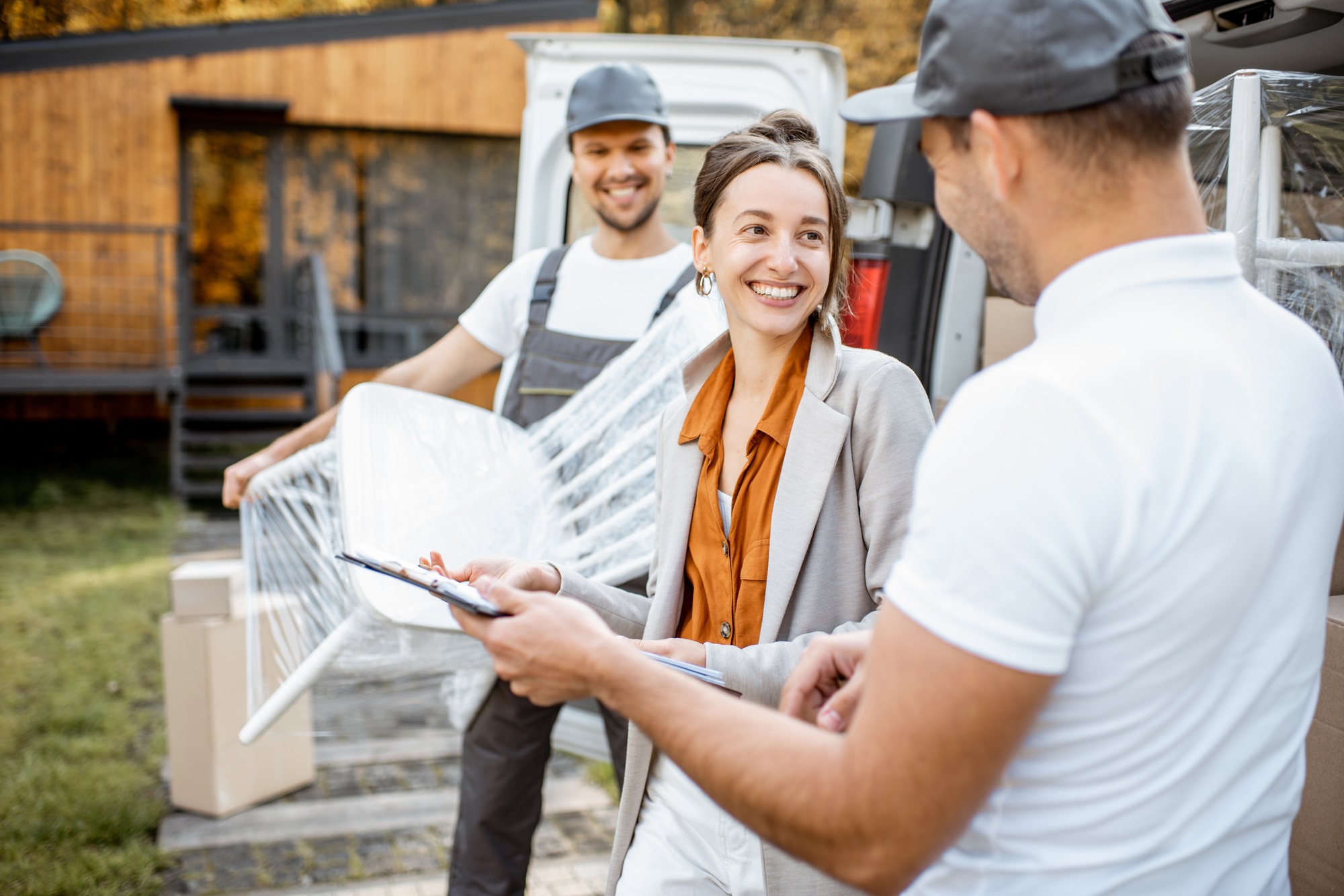 Assurance déménagement obligatoire : déménageurs souriants évaluant les détails sur une tablette avant emballage des meubles.
